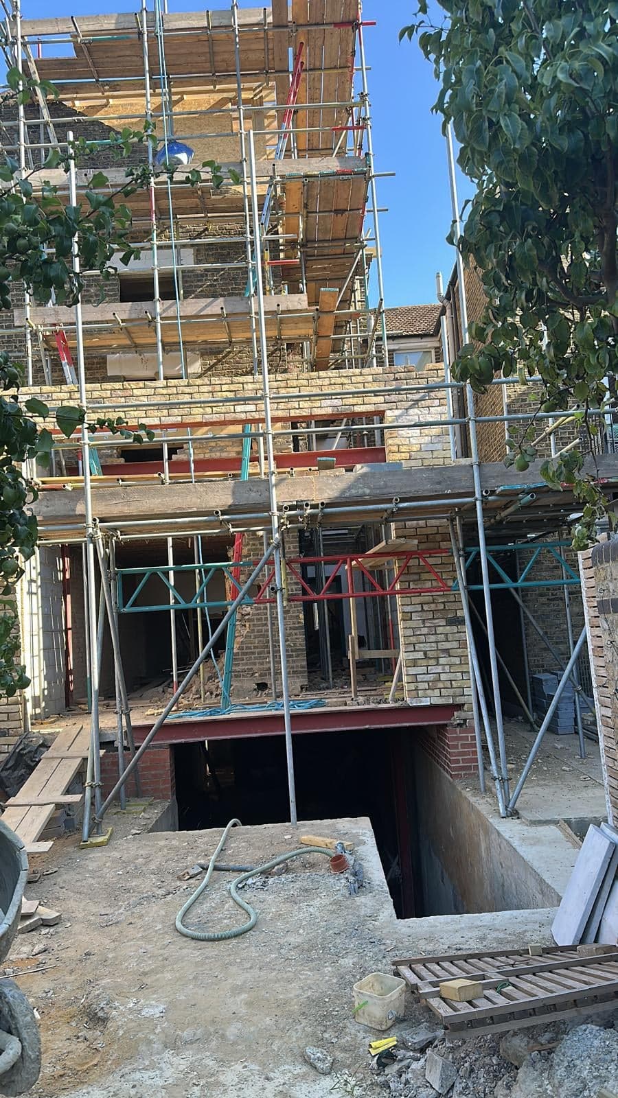 Front of a house under scaffold, dug out for the new basement and light well