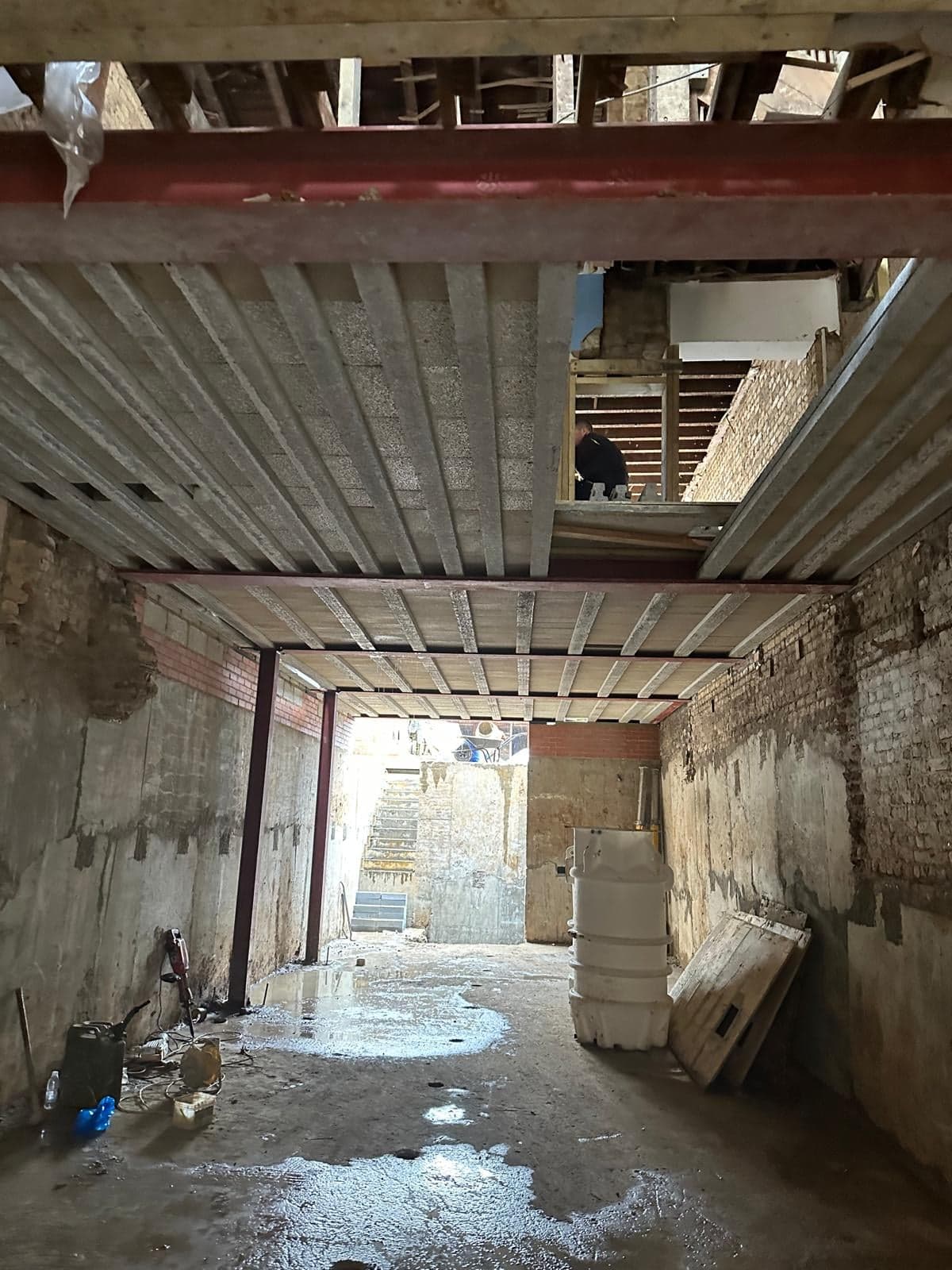 Bare basement shell under the new steel beams, before the waterproofing