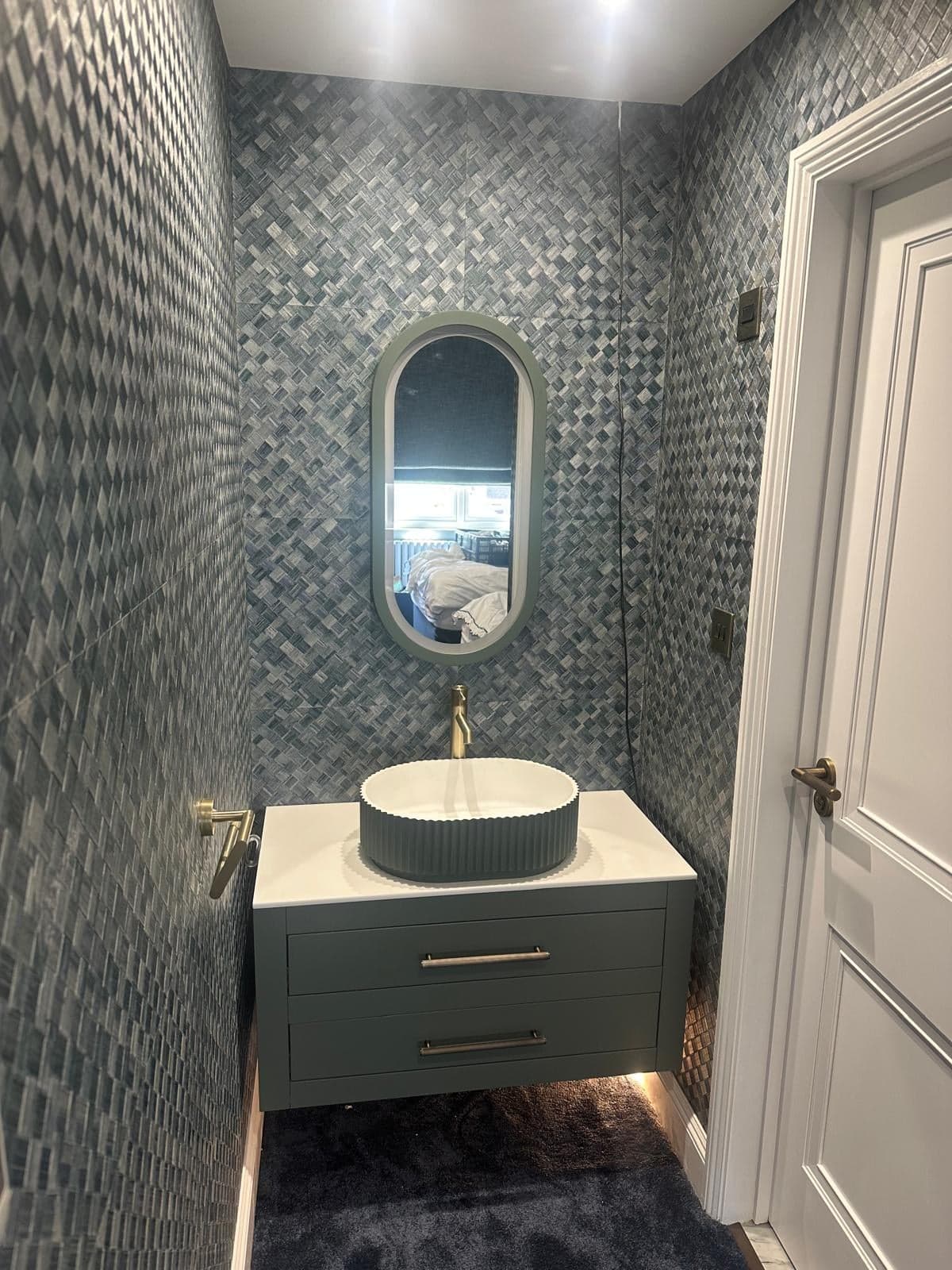 Cloakroom with textured tiles, a round basin and an oval mirror