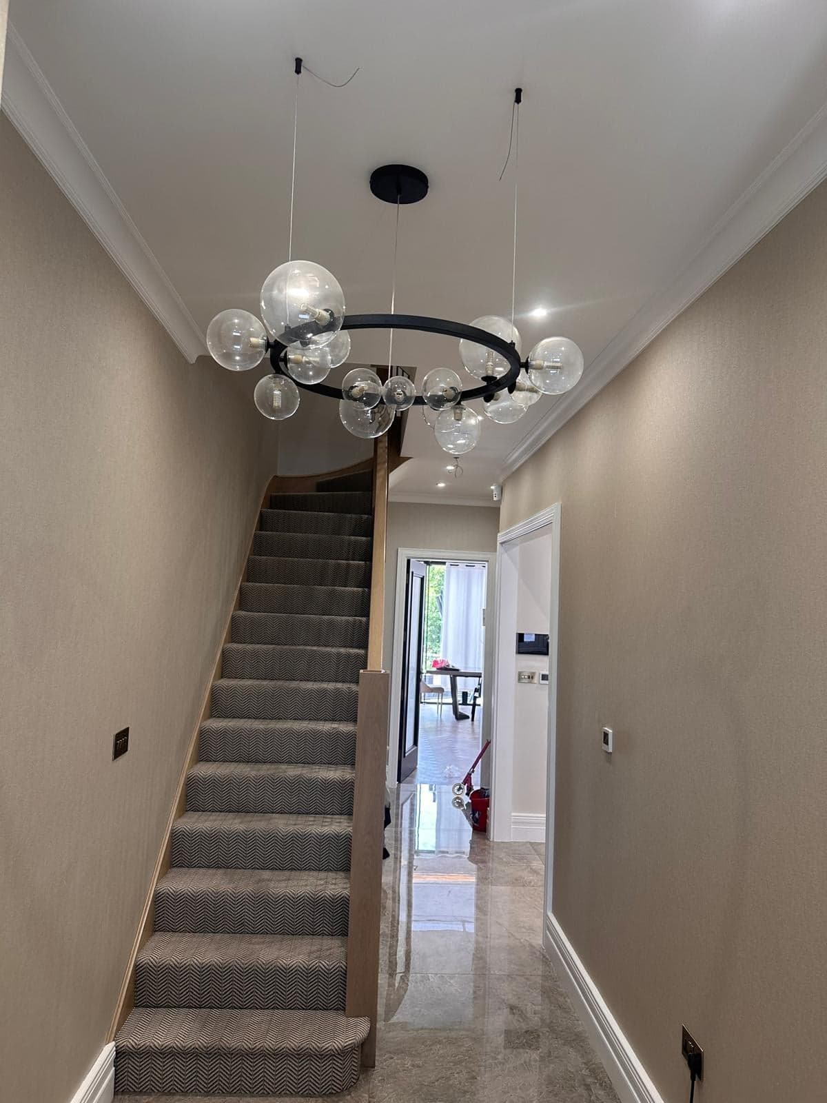 Refurbished hallway with a new stair runner, polished floor tiles and a globe chandelier