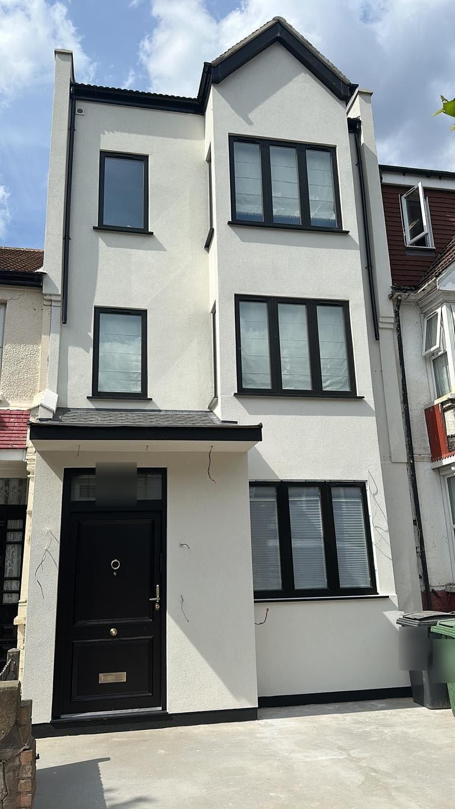 The same front finished in white render, with a new black front door and windows