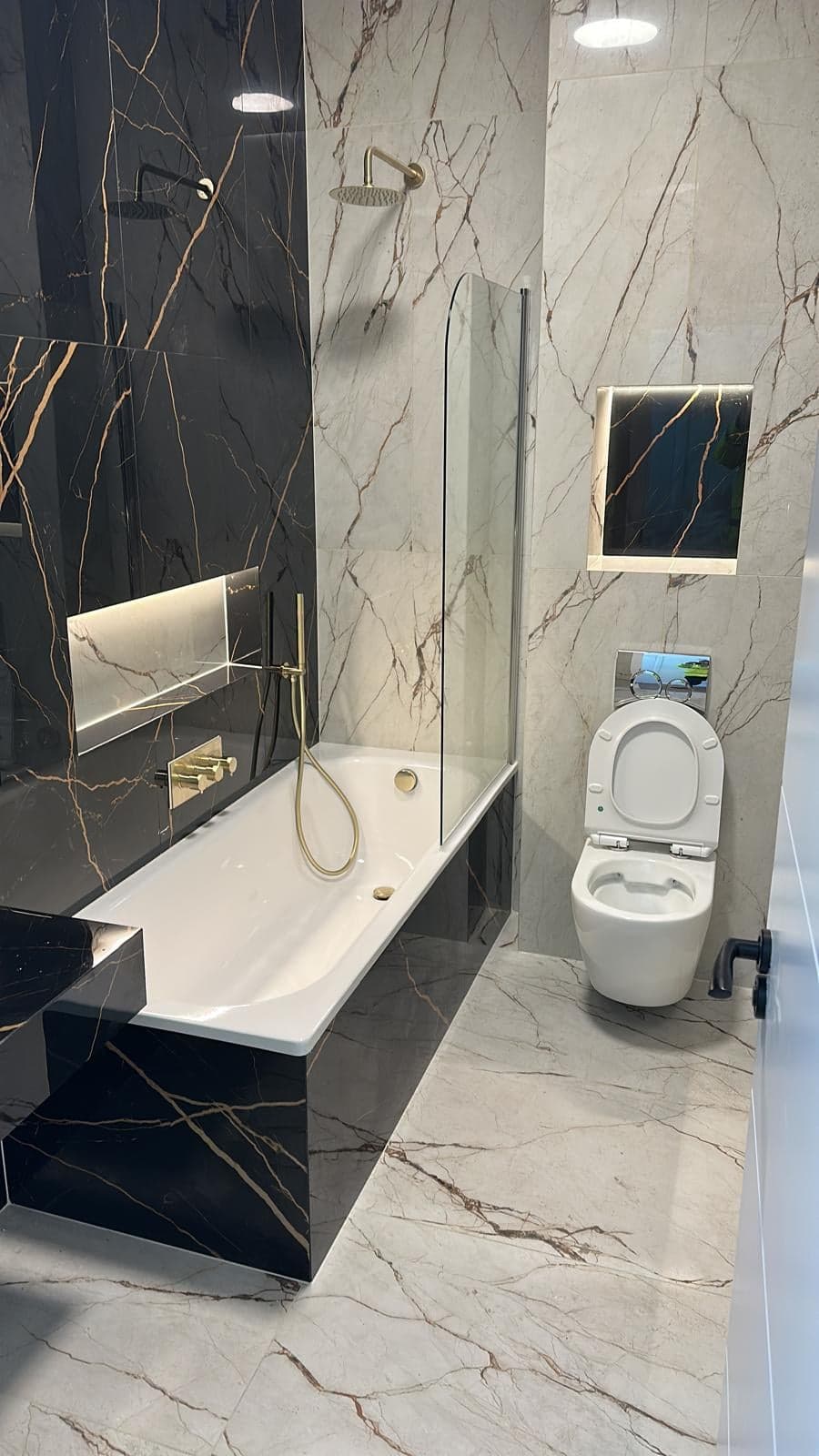 Bathroom in large marble-effect tiles with brass-coloured fittings